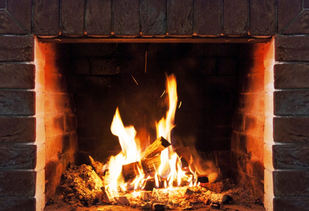 Close-up of wood logs and flames in a brick fireplace